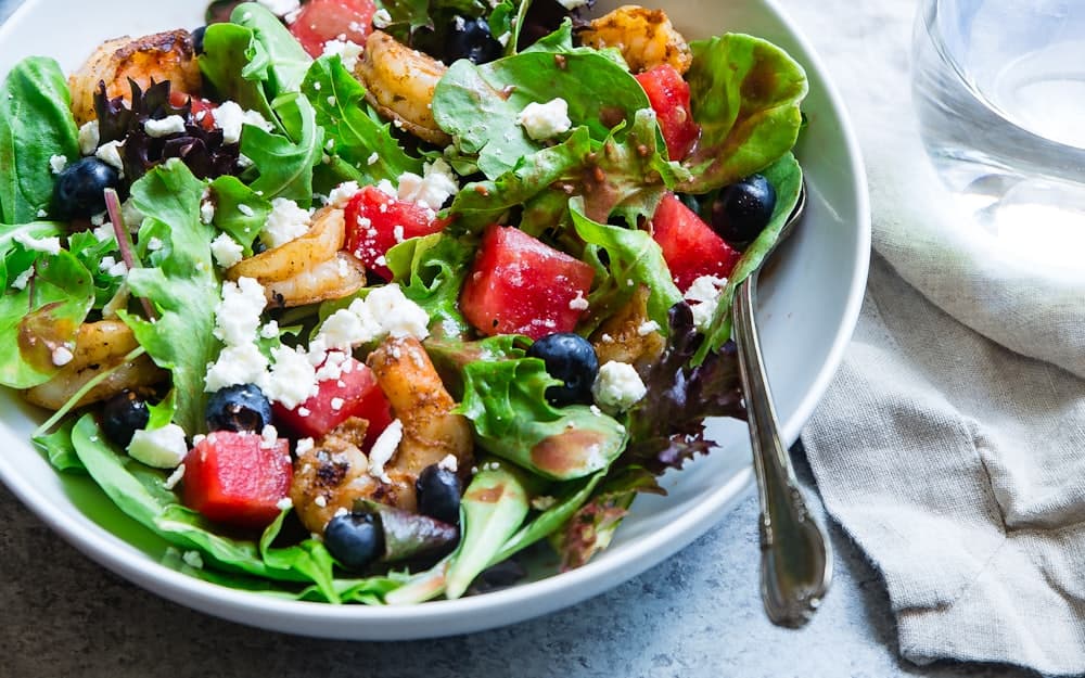 Tigela de salada com folhas verdes, frutas e queijo